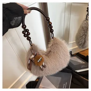Detalle de bolso de media luna de felpa con asa de cuentas de madera y dije