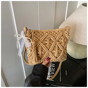 Detail of hand-woven beige crossbody bag with tassel and pearl lace bow accessory