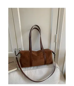 Detail of dark brown suede cylinder shoulder bag featuring premium texture and zipper
