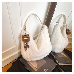Détail du sac hobo en fausse fourrure blanc cassé avec lanière en cuir et breloque chat