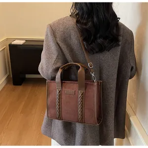 Detail of dark brown faux suede tote bag with leather handles and TOTE embossed tag