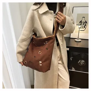 Close-up of brown suede tote bag with puppy embroidery and plush trim for autumn