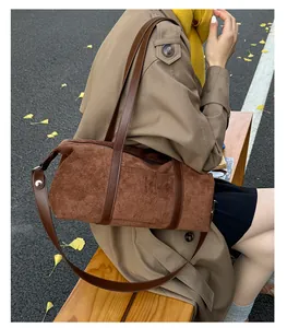 Detail of dark brown suede cylinder bag with leather trim on autumn park bench