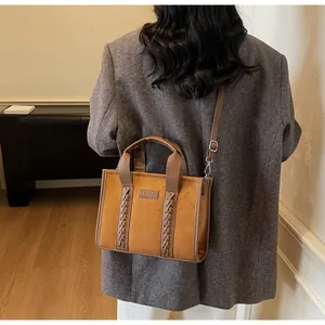 Detail view of camel suede tote bag with woven trim and adjustable crossbody strap