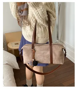 Detail view of khaki suede Boston bag with brown contrast leather handles and fuzzy pompom charm