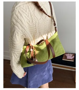 Detail view of the green suede crossbody bag with contrast strap and decorative charm