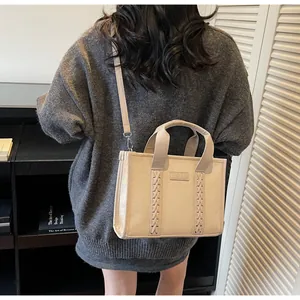 Close-up of beige suede tote bag with woven detail and TOTE embossed leather patch