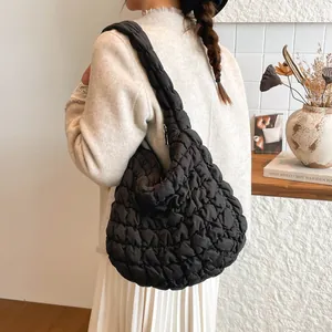 Bolso de hombro acolchado negro con textura de olas y correa ancha mostrado en modelo