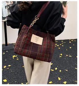 Classic red and green plaid wool tote bag with chain strap shown on person outdoors