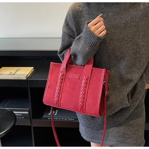 Detail of burgundy faux suede tote bag featuring woven decorative strips and embossed logo