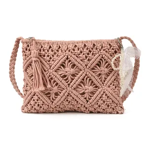 Pink macrame knit shoulder bag with bohemian fringe and pearl accent on white background