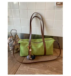 Detail of green suede baguette bag with leather straps and decorative fur pompom