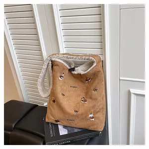 Detail of suede tote bag featuring puppy embroidery and soft fleece lining texture