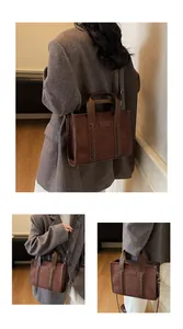 Detail of dark brown suede tote bag with woven leather straps and embossed TOTE label