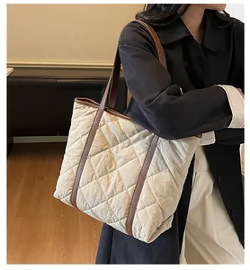 Detail of quilted tote bag with brown leather straps shown in a minimalist room setting