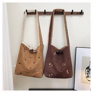 Detail view of suede tote bag with puppy embroidery, faux shearling lining, and horn buckle