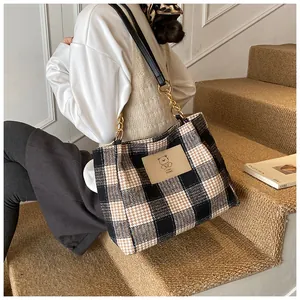 Detail view of houndstooth tote bag with leather bear patch and chain shoulder strap