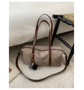 Detailed texture of brown suede baguette bag with plush pom-pom charms and leather strap