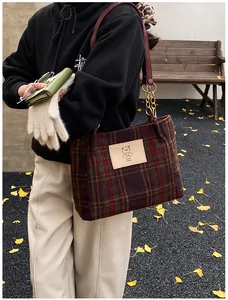 Detail of plaid tote bag with red leather strap and stylish golden chain link