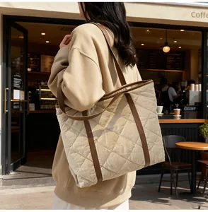 Quilted tote bag with leather straps shown on shoulder in a cozy cafe setting
