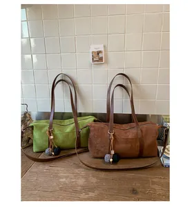 Detail of suede baguette bags in avocado green and caramel with fringe tassels
