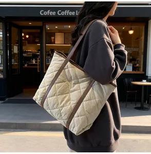 Detail of beige quilted tote bag with brown leather handles in a coffee shop setting