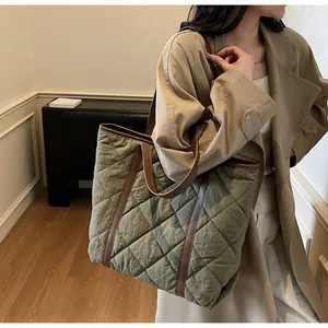 Detail of olive green quilted tote bag with brown leather handles and textured fabric