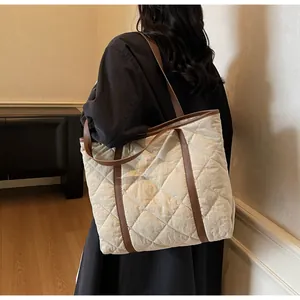 Detailed view of cream quilted tote bag with brown leather straps worn by model