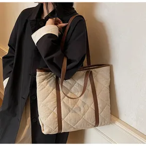 Close-up of lightweight quilted tote bag with brown leather handles on shoulder