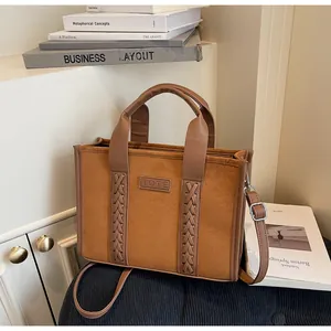 Detail of brown faux suede tote bag featuring embossed TOTE label and woven strap accents
