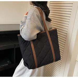 Quilted black nylon tote bag with brown shoulder straps shown on a model side view