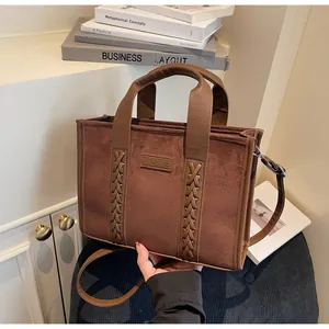 Detail of coffee suede tote bag with woven trim and leather TOTE label on front