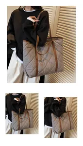 Detailed view of grey quilted tote bag with brown leather handles and contrast trim