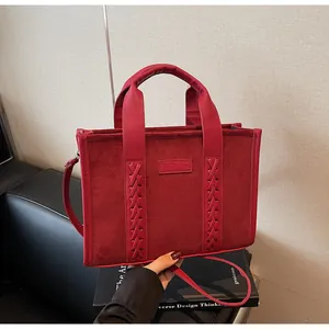 Detail of red faux suede tote bag featuring woven texture and leather handle