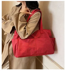 Détail du sac fourre-tout en toile à carreaux rouges avec doubles anses et poche latérale