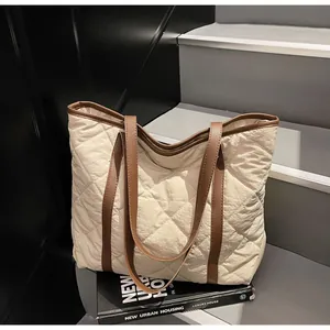Detail of quilted tote bag with brown leather handles placed on urban stairs