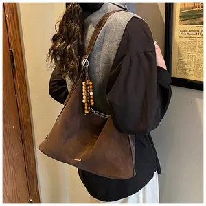 Detail of dark brown suede hobo bag featuring a beaded tassel and shoulder strap