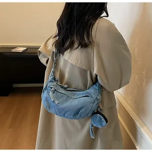 Detail of blue washed denim crescent bag with rustic frayed edges and mini coin purse