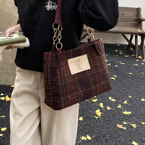 Retro red and green plaid tote bag with bear patch and chain strap in autumn setting
