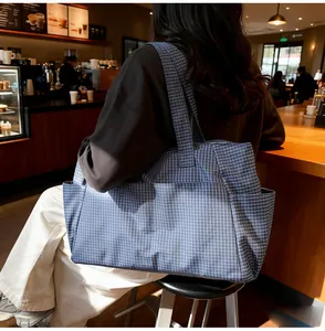 Gros plan du sac cabas en toile à carreaux bleus montrant la poche latérale et le tissu