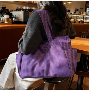 Détail d'un grand sac cabas en toile à carreaux violets porté par un mannequin au café
