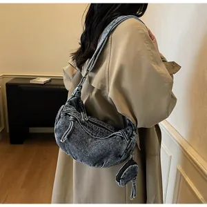 Detail der vintage gewaschenen Denim-Halbmondtasche mit rundem Münzfach an der Schulter