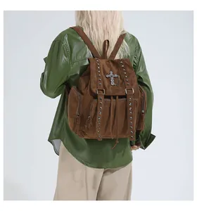 Detailed view of the vintage brown suede backpack featuring metallic studs and cross pendant