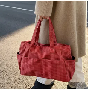 Détail d'un grand sac fourre-tout à carreaux rouges avec poches latérales et modèle