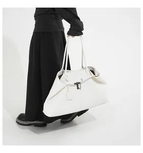 Detail of large white leather shoulder bag featuring a sleek black metal T-shaped buckle