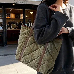 Olive green quilted tote bag with brown leather straps shown in an outdoor setting