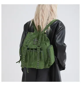 Detail of forest green suede backpack with silver studs and metal cross charm on model
