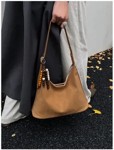 Detail of tan faux suede hobo bag with colorful wooden bead charm and minimalist shoulder strap