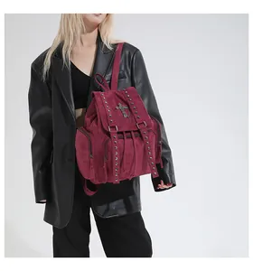 Detail of burgundy gothic backpack with metallic rivets and a cross pendant on a model