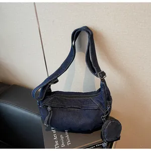Detail of dark blue washed denim dumpling bag with adjustable strap and coin purse